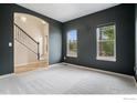 A carpeted living room with a view of the staircase and with two bright windows at 6725 2Nd St, Frederick, CO 80530