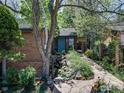 Inviting home with brick facade, mature trees, and a blue front door surrounded by rock garden at 700 Poplar Ave, Boulder, CO 80304