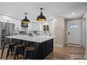 Bright kitchen with a large island, white cabinets, stainless steel appliances, and modern pendant lighting at 8334 Allison Ct, Arvada, CO 80005