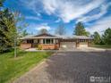 A view of this ranch-style home with a three-car garage and mature landscaping at 11361 Flatiron Dr, Lafayette, CO 80026
