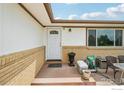 Inviting front porch with brick accents, white door with glass, and decorative plants at 12734 Anhawa Ave, Longmont, CO 80503