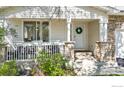 Close up of the charming front porch with stone pillars and a white wreath on the door at 1304 Monarch Ct, Longmont, CO 80504