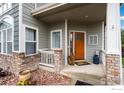 Inviting covered front porch area with stone accents and a charming wooden door, showcasing curb appeal at 2193 Sand Dollar Cir, Longmont, CO 80503