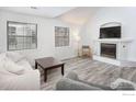 Bright living room with vaulted ceilings, a cozy fireplace, two large windows, and modern light gray wood-look flooring at 2317 Walnut St, Boulder, CO 80302