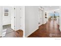 Bright hallway featuring hardwood floors, white walls, and access to various rooms, creating a seamless flow at 2422 E 156Th Pl, Thornton, CO 80602