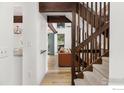 Staircase with wood banister leading to an open living space with wood floors and beamed ceilings at 4100 Greenbriar Blvd, Boulder, CO 80305