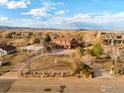 Aerial view of property with red house, an outbuilding, rock wall, landscaping, and blue skies at 4963 Kelso Rd, Boulder, CO 80301