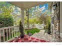 Relaxing front porch, adorned with a red rug and a view of a lush green lawn, white picket fence, and trees at 5134 Ladies Tresses Pl, Broomfield, CO 80023