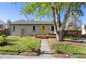 Single story home with a lush green yard, mature tree, and inviting yellow front door at 6260 W 61St Ave, Arvada, CO 80003