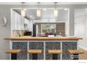 Open kitchen view featuring stylish mosaic tiling, wooden bar, and modern pendant lighting at 6260 W 61St Ave, Arvada, CO 80003
