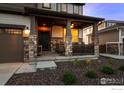 Inviting front porch with stone pillars, seating area, and views of the professionally landscaped yard at 647 Boulder Peak Ave, Erie, CO 80516