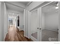 Bright hallway with hardwood floors leading to a home office with glass french doors at 647 Boulder Peak Ave, Erie, CO 80516