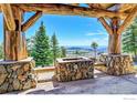 Outdoor entertainment area with stone fireplace and seating showcasing panoramic mountain views at 6553 Sunshine Canyon Dr, Boulder, CO 80302