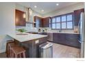 Contemporary kitchen features an island with seating, stainless steel appliances, and sleek dark wood cabinetry at 7861 W 51St Ave, Arvada, CO 80002