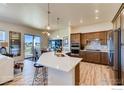 Modern kitchen featuring an island with quartz countertops, stainless steel appliances and wood flooring at 903 W 129Th Pl, Westminster, CO 80234