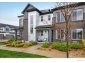 Stylish townhome featuring a blend of brick and corrugated metal exterior, complete with a cozy front porch and verdant lawn at 9305 S Gore St # C, Arvada, CO 80007