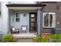 Inviting front porch with seating, corrugated metal siding, brick accents, and well-maintained landscaping at 9305 S Gore St # C, Arvada, CO 80007
