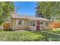 Charming yellow house with a red door, enclosed front porch, and well-maintained lawn at 1136 Venice St, Longmont, CO 80501