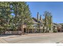 Exterior view of the Ashley Court condominium complex with mature trees and landscaping at 1300 S Monaco Pkwy # 12, Denver, CO 80224