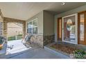 Welcoming front porch featuring stone accents, a seating area, and a decorative glass front door at 14180 Whitney Cir, Broomfield, CO 80023