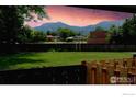 A serene backyard with a lush lawn, wooden fence, and a stunning mountain view at 4150 Monroe Dr # C, Boulder, CO 80303