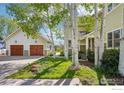 A well-maintained home with a detached two-car garage, mature trees, and lush landscaping at 474 W Spruce St, Louisville, CO 80027