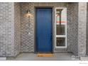Inviting blue front door with gray brick surround and a 'hello' welcome mat at 5173 Vivian St, Wheat Ridge, CO 80033