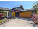 Contemporary home with a statement yellow door, wood garage door, and attractive landscaping at 6862 Roaring Fork Trl, Boulder, CO 80301