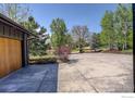Garage featuring a complementary wood door with a large driveway surrounded by mature trees at 6862 Roaring Fork Trl, Boulder, CO 80301