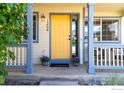Inviting front porch with yellow door, fresh flowers, and seating area creates a welcoming entrance to the home at 1264 Banner Cir, Erie, CO 80516