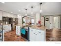 Spacious kitchen features an island with seating, stainless appliances, granite countertops, and wood flooring at 13106 Elizabeth St, Thornton, CO 80241
