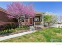 Inviting front yard showcasing a lush lawn, vibrant flowers, and mature landscaping around a cozy front porch at 13668 Plaster Cir, Broomfield, CO 80023