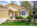 Lovely yellow home showcasing a manicured lawn, beautiful flowerbeds, and an attached two-car garage at 1606 Iris St, Broomfield, CO 80020