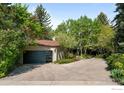Contemporary home featuring a modern garage with sleek doors, nestled amongst mature trees and landscaping at 3945 Promontory Ct, Boulder, CO 80304