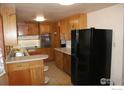 Traditional kitchen with wood cabinets, tiled floor, double basin sink, and black refrigerator at 6363 County Road 20, Longmont, CO 80504