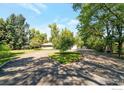 Wide shot of a beautiful single-story house with a circular driveway and lots of trees at 8813 Baseline Rd, Lafayette, CO 80026