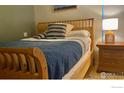 Cozy bedroom with a wooden bed frame, stylish striped pillows, and a woven lamp on a nightstand at 1111 Maxwell Ave # 109, Boulder, CO 80304
