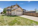 Side view of a home with a well-maintained lawn and a long driveway leading to a garage at 2104 18Th Ave, Longmont, CO 80501