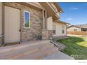 Inviting front entrance with stone accents, steps, and a cozy porch seating area at 2104 18Th Ave, Longmont, CO 80501