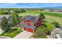 Aerial view of the red two-story home with surrounding green spaces and neighborhood at 2290 Cottonwood Pl, Erie, CO 80516