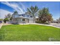 View of home's well-manicured front lawn, side entrance, and three-car garage at 2410 Key Ct, Longmont, CO 80501