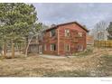 The back of the two-story home has a wooden deck, and a patio area for outdoor enjoyment at 26167 De Berry St, Conifer, CO 80433