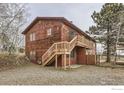 Two-story home with a wooden staircase leading to a deck, surrounded by gravel landscaping at 26167 De Berry St, Conifer, CO 80433