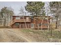 Two-story home with wood siding, a deck, and a pergola, set on a gravel lot with mountain views at 26167 De Berry St, Conifer, CO 80433