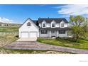 Attractive two-story white farmhouse-style home with a covered front porch, well-maintained lawn, and a paved driveway at 5306 Foothills Dr, Berthoud, CO 80513