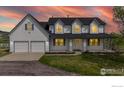 Charming two-story home with a welcoming front porch illuminated by warm lights and a lovely sunset backdrop at 5306 Foothills Dr, Berthoud, CO 80513