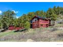 Charming two story home featuring a solar panel, nestled among mature trees, and sloping grass yard at 548 Coughlin Meadows Rd, Boulder, CO 80302