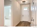 Bright entryway with hardwood floors, a stylish light fixture, and a glass-paneled front door at 5901 Aspenglow St, Longmont, CO 80504