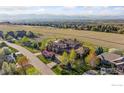 An aerial view shows a luxury home, large grassy yard, landscaping, and scenic views of mountains in the distance at 6541 Legend Ridge Trl, Niwot, CO 80503