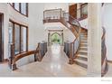 A grand foyer with a curved staircase, tile flooring, a view of the manicured front yard, and arched doorways at 6541 Legend Ridge Trl, Niwot, CO 80503